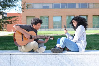 Gitar çalan genç Latin bir adam ve üniversite kampüsünde onu akıllı telefonla kaydeden arkadaşı. Üniversite hayatı, bin yıllık nesil..