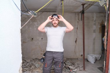 İnşaat alanında güvenlik gözlüğü takan genç bir müteahhit. Koruyucu gözlük takan adam..