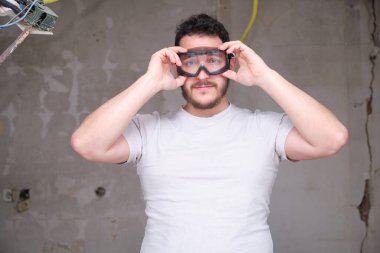 İnşaat alanında güvenlik gözlüğü takan genç bir müteahhit. Koruyucu gözlük takan adam..