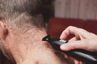 Kadın evde saç kesme makinesi ya da saç kesme makinesiyle kocasını kesiyor..