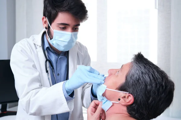 Olgun bir kadın koronavirüs salgını sırasında PCR testi yaptırıyor. Doktor eldiven ve maske takarak burun koronavirüsü testi yapıyor..