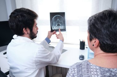 Kafatasının röntgenini çeken genç bir doktor, olgun bir kadın hastayla sinüsler. Bir baş radyolojisi.