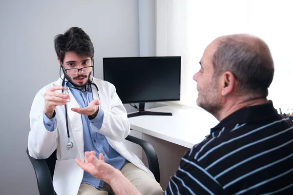 Ung Läkare Hälso Och Sjukvårdspersonal Förskriva Medicin Till Äldre Man — Stockfoto