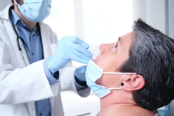 Olgun bir kadın koronavirüs salgını sırasında PCR testi yaptırıyor. Doktor eldiven ve maske takarak burun koronavirüsü testi yapıyor..