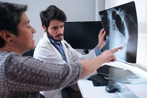 Joven Médico Examinando Radiografía Una Costilla Rota Con Una Paciente —  Fotos de Stock