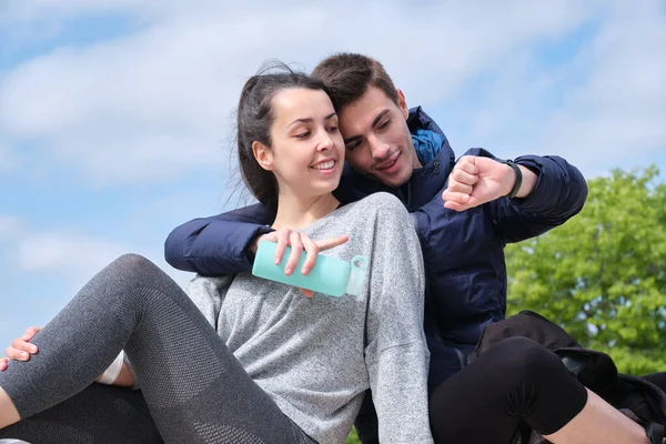 Feliz Joven Pareja Deportiva Mirando Smartwatch Mientras Está Sentado Parque — Foto de Stock