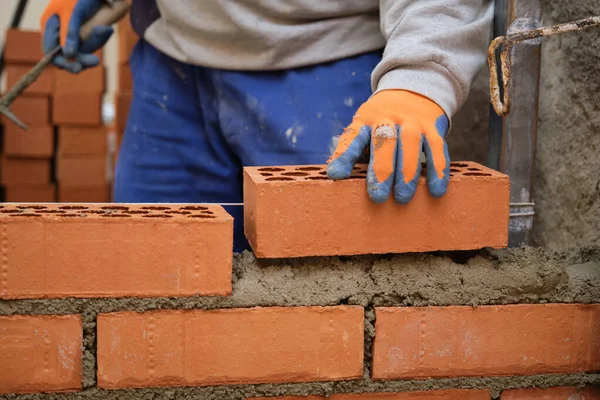 İnşaat işçisi duvar örüyor. Tuğla döşeme. Mason tuğla döşüyordu.