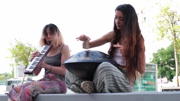 两个女人坐在街上 弹奏着手锅和吹奏着旋律的管风琴 — 图库视频影像