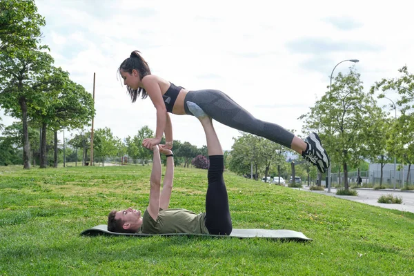 Giovane coppia sportiva praticare acro-yoga volare posa sull'erba — Foto Stock
