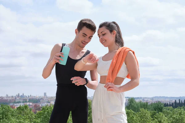 Glad ung sport par tittar på fitness tracker nära stående — Stockfoto