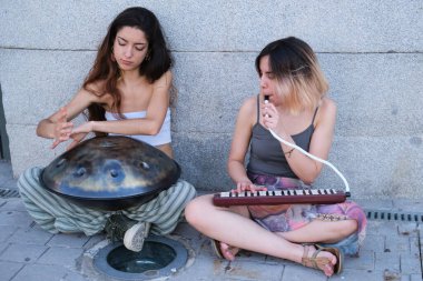İki kadın yerde oturmuş pervane ve melodi çalıyorlar..