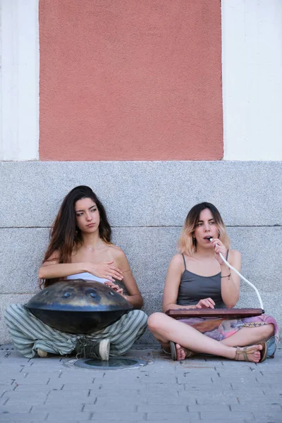 Twee vrouwen die handpan en melodica blaasorgels spelen op de vloer. — Stockfoto