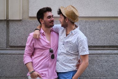 Genç eşcinsel çift birbirine sarılıyor ve gülümsüyor..