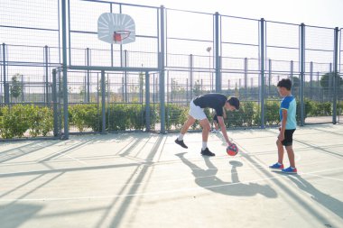 Koltuk iki öğrenciyle futbol oynuyor. Bir tanesinin bacak protezi var ve penaltıları tekmeliyorlar..