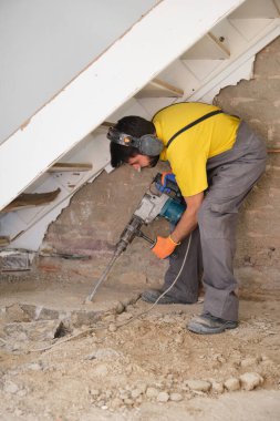 Genç müteahhit bir kaya matkabıyla evin zeminini yıkıyor..