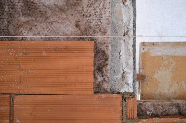 Duvarla tuğla tabaka arasına koyulan kahverengi yünlü battaniye..