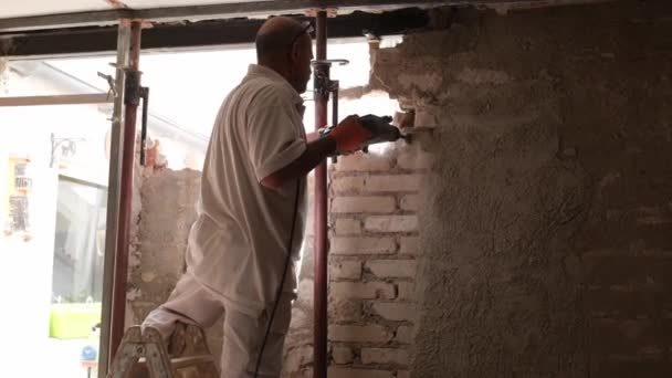 Constructor con martillo de demolición rompiendo una pared de la casa. — Vídeos de Stock
