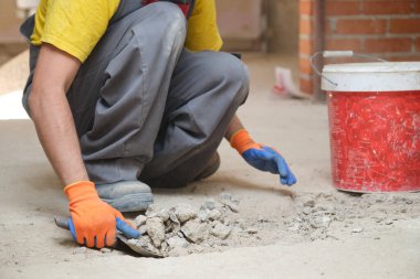 Tanımlanamayan genç inşaatçı inşaat alanında kum kürüyor..