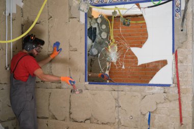 Mason çekiçle ayna kırıyor. Ev yenilenmesi.