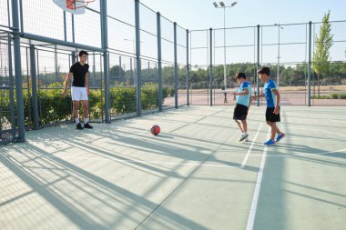 Koltuk iki öğrenciyle futbol oynuyor. Bir tanesinin bacak protezi var ve penaltıları tekmeliyorlar..
