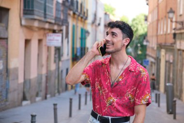 Uzun takma tırnakları olan, gülümseyen ve akıllı telefondan konuşan beyaz bir genç..