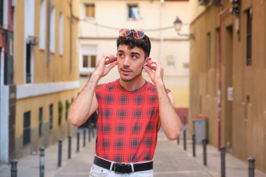 Sokakta kablosuz kulaklıklarını takan uzun takma tırnaklı beyaz bir genç..