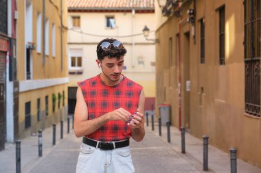 Sokakta kablosuz kulaklıklarını takan uzun takma tırnaklı beyaz bir genç..