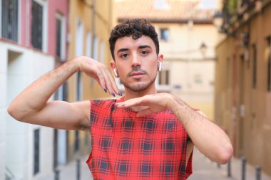 Uzun takma tırnakları olan ve kollarıyla poz veren beyaz bir adamın portresi..