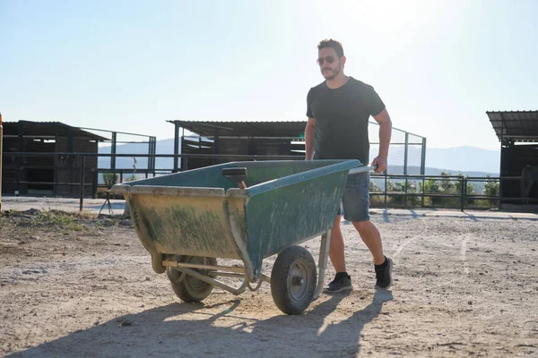 Jonge Latijnse Man Met Een Kruiwagen Paardenuitwerpselen Halen Een Stal — Stockfoto