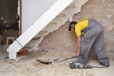 Kafkasyalı genç inşaat işçisi levyeyle evin zeminini kırıyor..
