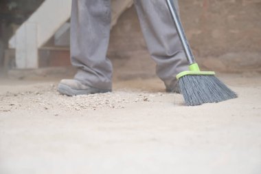 Bir inşaat alanında zemini süpüren Kafkasyalı genç bir inşaat işçisinin yakınına..
