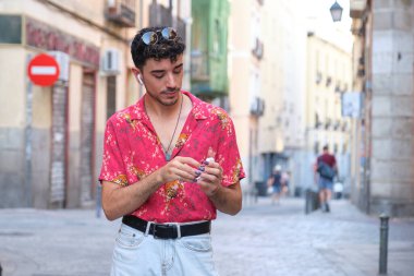 Sokakta kablosuz kulaklıklarını takan uzun takma tırnaklı beyaz bir genç..