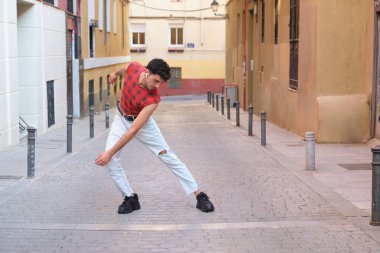 Sokakta dans eden uzun takma tırnaklı beyaz bir genç, çağdaş dans adımları..