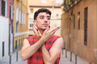 Uzun takma tırnakları olan ve kollarıyla poz veren beyaz bir adamın portresi..