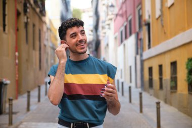 Sokakta kablosuz kulaklıklarını takan uzun takma tırnaklı beyaz bir genç..