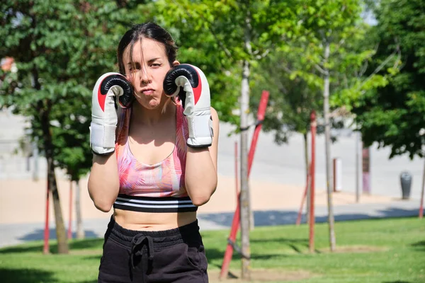 Jeune femme en gants de boxe prêt à se battre en regardant la caméra. — Photo