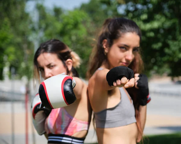 Jovens mulheres em luvas de boxe batendo e olhando para a câmera. — Fotografia de Stock