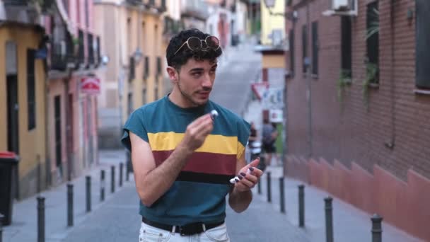 Jonge Kaukasische man met lange valse nagels zetten op zijn draadloze oordopjes. — Stockvideo