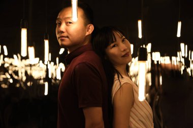 Genç Asyalı çift ışık ve aynalarla dolu bir odada gülümsüyor..