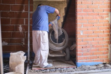 İnşaat işçisi beton karıştırıcıya kum torbası yüklüyor..