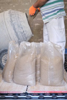 İnşaat işçisi beton karıştırıcıya kum torbası yüklüyor..