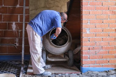 İnşaat işçisi karıştırıcıdaki betonun kalitesini kontrol ediyor..