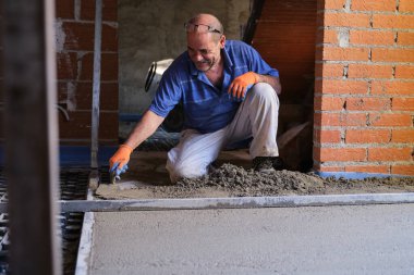 İnşaat işçisi gülümseyip etrafa beton saçıyor..