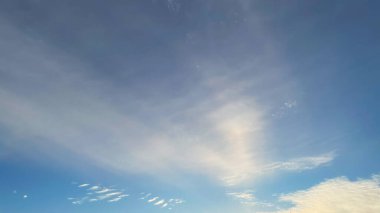 Mavi gökyüzü, hafif ve yumuşak, çizgili beyaz bulutlarla. Sakin ve huzurlu bir atmosfer.