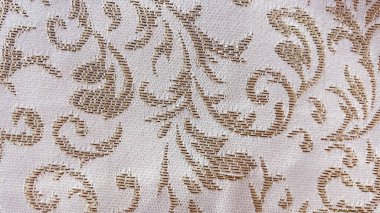 Örülmüş altın metalik çiçek desenli zarif bej kumaş. Klasik lüks tekstil makro dokusu