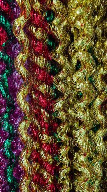 Şenlik arka planı için kırmızı, yeşil ve mor renklerle süslenmiş dalgalı çizgili metalik çelenklerin soyut dokusu