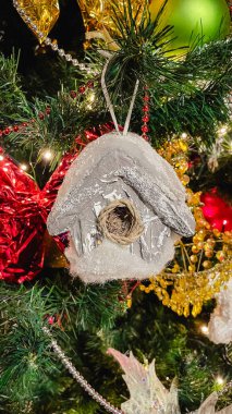 Beyaz bir melek figürü, kırmızı boncuklar ve sıcak peri ışıklarıyla süslenmiş bir Noel ağacının yakın çekimi..