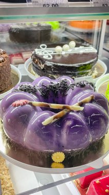 Zarif mor ayna jöleli kremalı pasta. Çikolata süslemeleri bir pastanede sergileniyor.