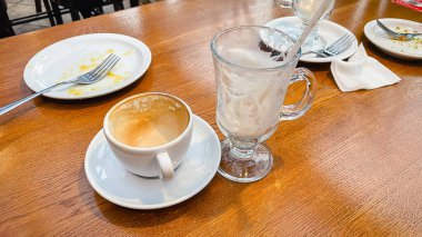 Kahvede kahvaltıdan sonra kirli tabakları olan boş kahve fincanı ve cam bardak.