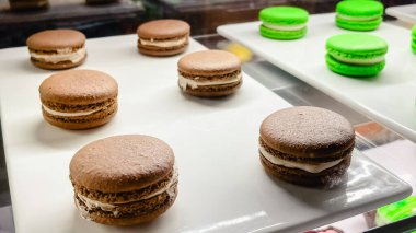 Taze çikolata ve kafedeki beyaz tepside sergilenen kremalı yeşil şam fıstıklı badem kurabiyesi.